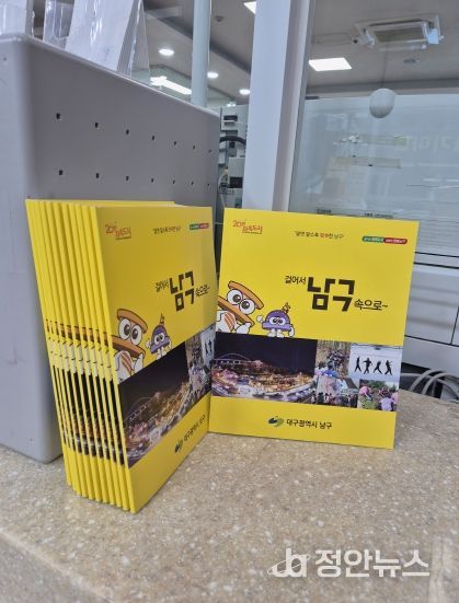 전입신고하는 주민에게 전입자를 위한 남구 안내서를 건네주고 있다.